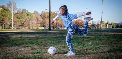 girl kicking ball on a field